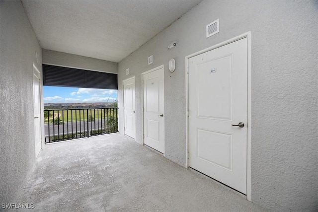 interior space featuring a textured ceiling, visible vents, concrete flooring, and a textured wall