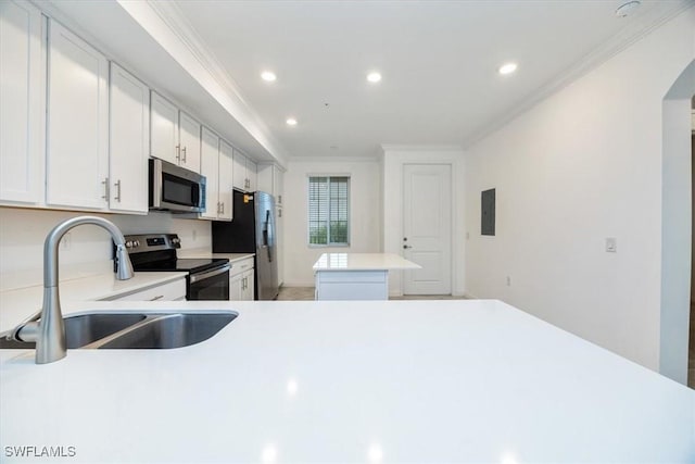 kitchen with crown molding, light countertops, appliances with stainless steel finishes, white cabinets, and a sink