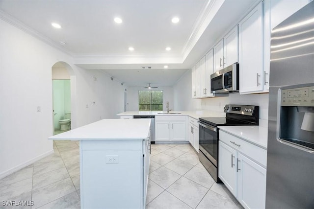 kitchen with light countertops, appliances with stainless steel finishes, white cabinets, a sink, and a peninsula