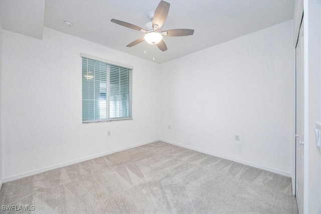 empty room featuring light colored carpet, ceiling fan, and baseboards