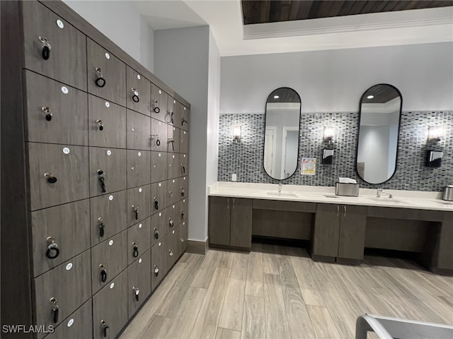 bathroom featuring double vanity, decorative backsplash, a sink, and wood finished floors