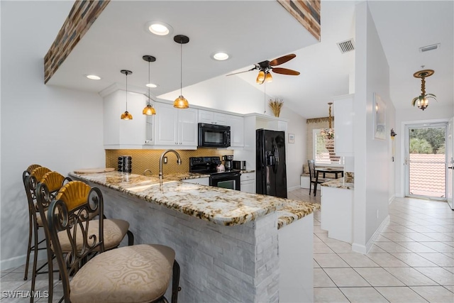 kitchen featuring white cabinets, black appliances, kitchen peninsula, and a breakfast bar area