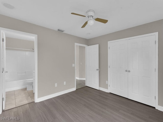 unfurnished bedroom with dark hardwood / wood-style flooring, a closet, ceiling fan, and ensuite bathroom