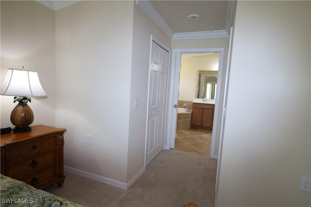 hallway featuring baseboards, crown molding, and light colored carpet
