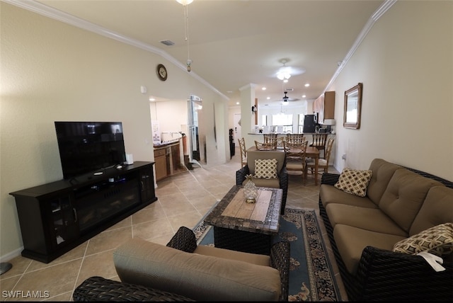 living area featuring light tile patterned flooring, visible vents, ornamental molding, and vaulted ceiling