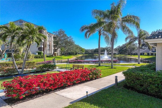 surrounding community with a water view and a lawn