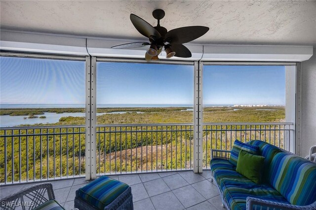 sunroom / solarium featuring ceiling fan and a water view