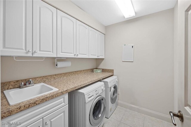 laundry area with sink, light tile patterned floors, cabinets, and independent washer and dryer