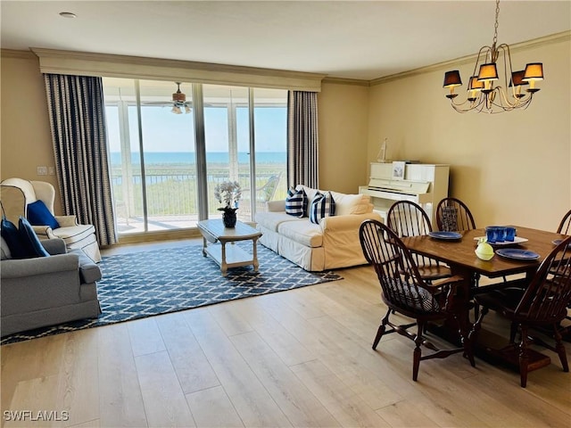 dining space with crown molding, a water view, and light wood finished floors