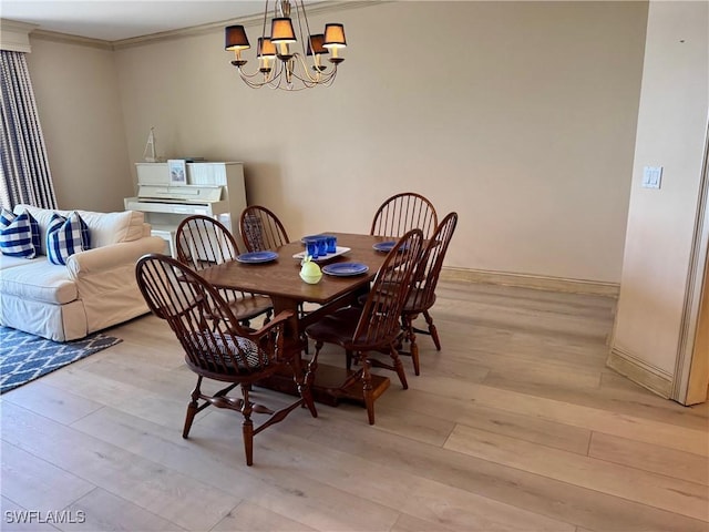 dining space featuring a chandelier, baseboards, ornamental molding, and light wood finished floors