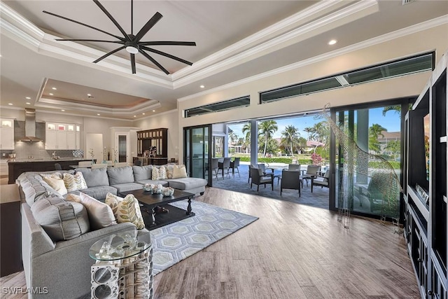 living room with hardwood / wood-style floors, a tray ceiling, ceiling fan, and crown molding