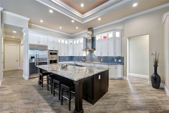 kitchen with wall chimney exhaust hood, a spacious island, white cabinetry, and appliances with stainless steel finishes