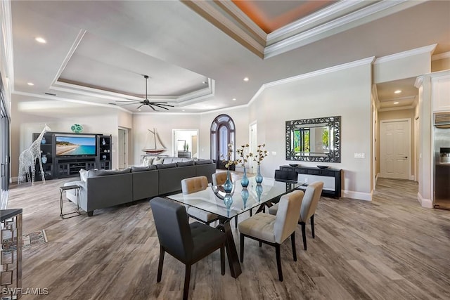 dining area featuring a raised ceiling, crown molding, ceiling fan, and hardwood / wood-style flooring