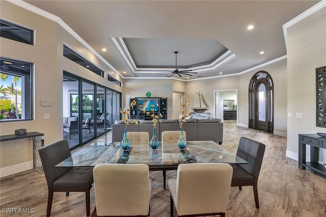 dining area with light hardwood / wood-style flooring, a raised ceiling, ceiling fan, and crown molding