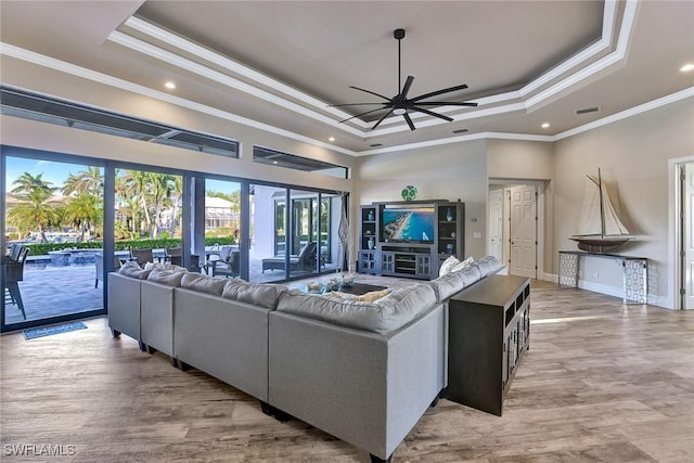 living room featuring a raised ceiling, crown molding, and ceiling fan