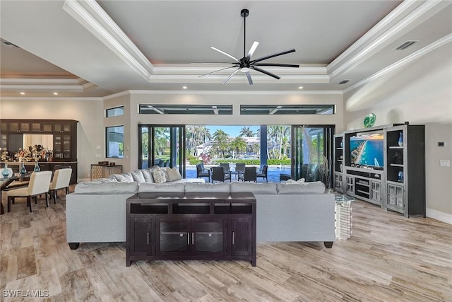 living room featuring a raised ceiling, a wealth of natural light, and ornamental molding