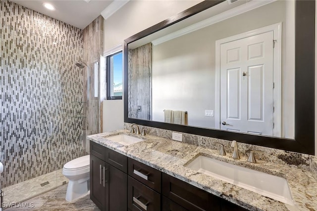 bathroom with a tile shower, vanity, toilet, and crown molding