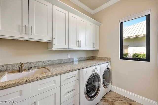 laundry room featuring cabinets, sink, crown molding, washing machine and dryer, and light hardwood / wood-style floors