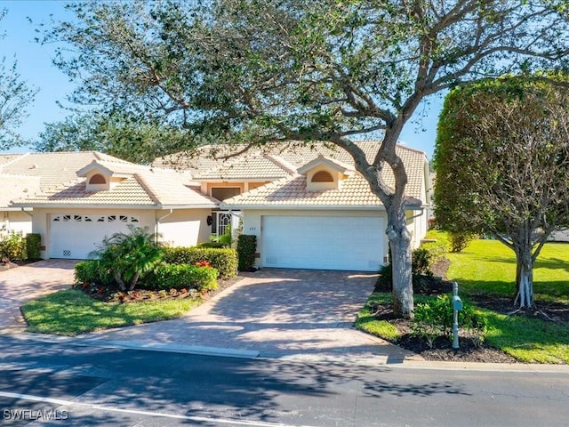 view of front of property with a tiled roof, decorative driveway, an attached garage, and stucco siding