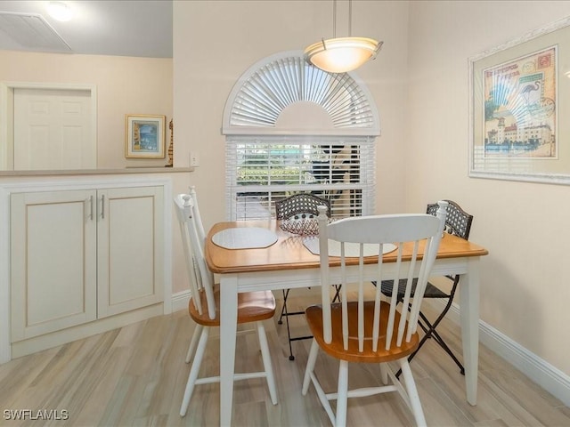 dining area featuring baseboards and light wood finished floors