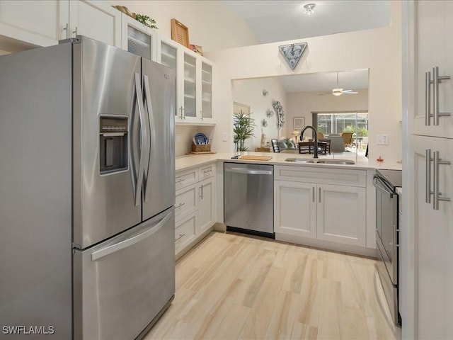 kitchen featuring stainless steel appliances, glass insert cabinets, a sink, and light countertops