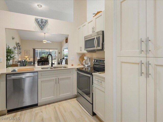 kitchen with white cabinetry, sink, ceiling fan, stainless steel appliances, and kitchen peninsula