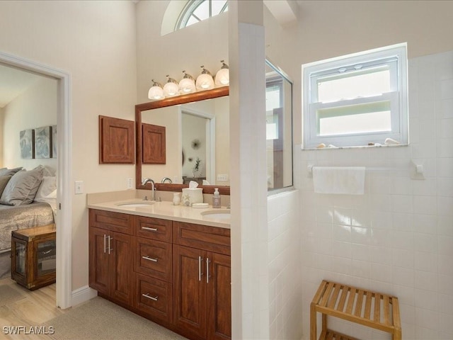 full bath with connected bathroom, walk in shower, a sink, and double vanity