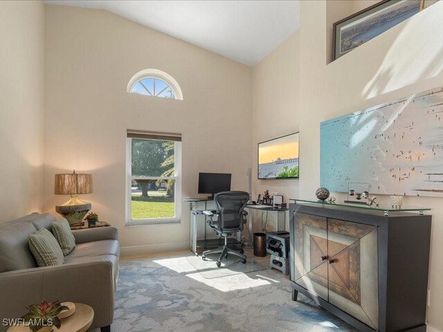 office featuring plenty of natural light, light colored carpet, and high vaulted ceiling