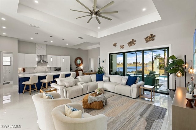 living room featuring ceiling fan and a tray ceiling