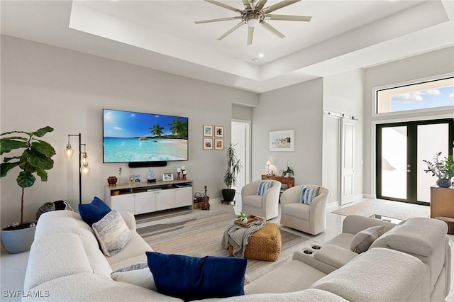 living room featuring french doors, a tray ceiling, and ceiling fan