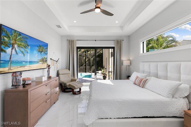 bedroom featuring ceiling fan, multiple windows, access to outside, and a tray ceiling