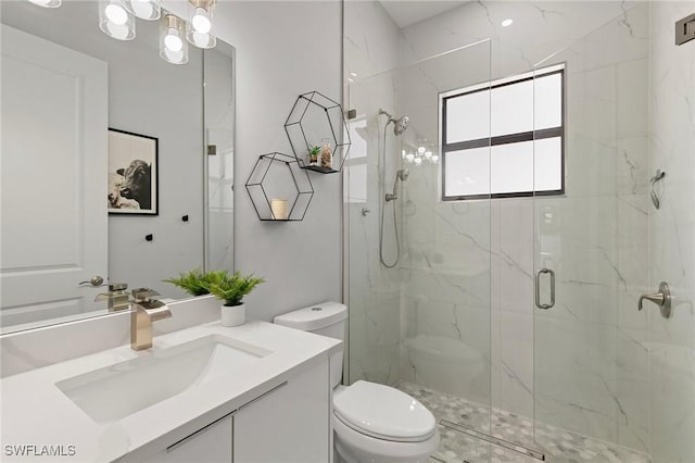 bathroom with a shower with door, vanity, and toilet