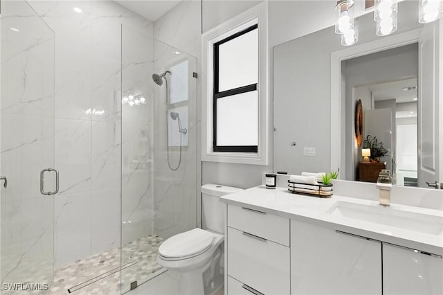 bathroom featuring a shower with door, vanity, plenty of natural light, and toilet