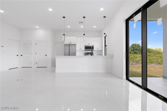 kitchen with decorative light fixtures, white cabinetry, and stainless steel appliances