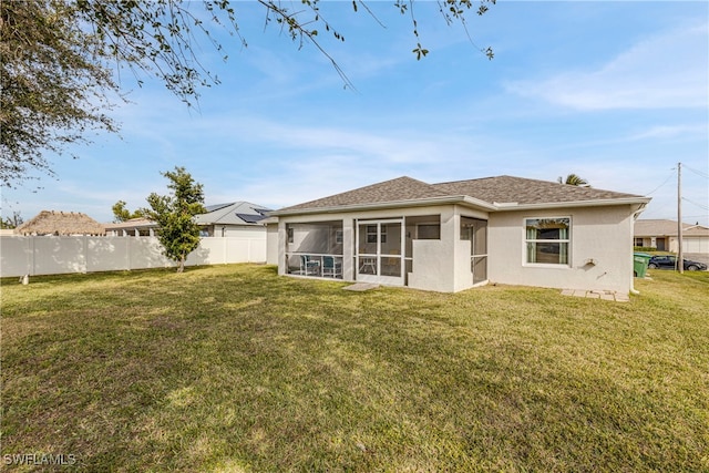 rear view of property featuring a yard and a sunroom