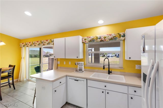 kitchen featuring sink, white appliances, white cabinets, light tile patterned flooring, and kitchen peninsula