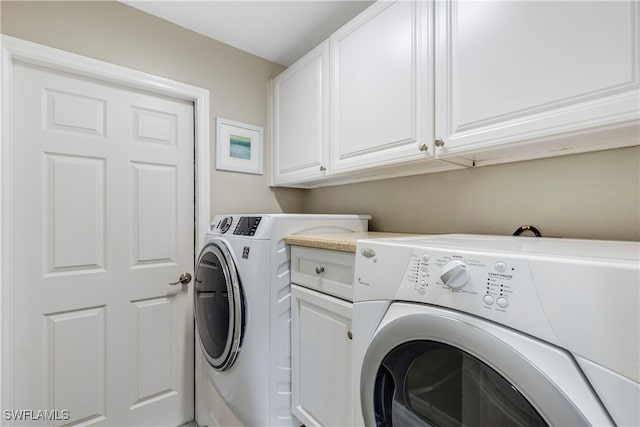 clothes washing area with cabinets and washer and dryer