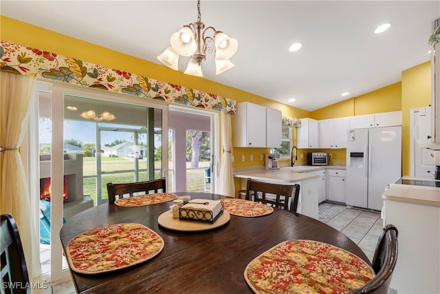 tiled dining room featuring lofted ceiling, sink, and a chandelier