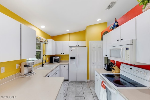 kitchen with white appliances, vaulted ceiling, and white cabinets