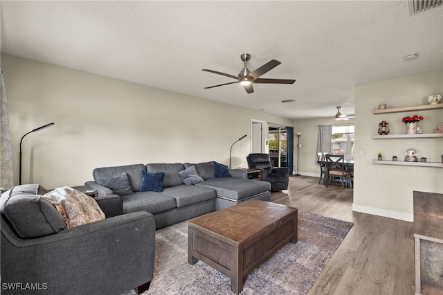 living room featuring a textured ceiling, ceiling fan, and dark hardwood / wood-style flooring