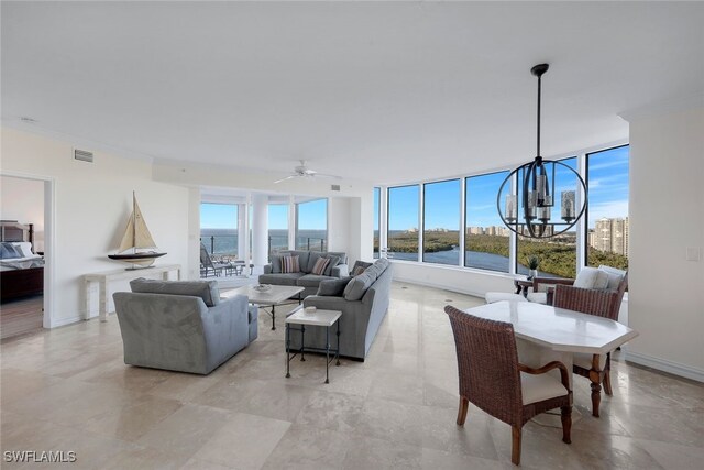 living room featuring ceiling fan with notable chandelier, ornamental molding, and a water view