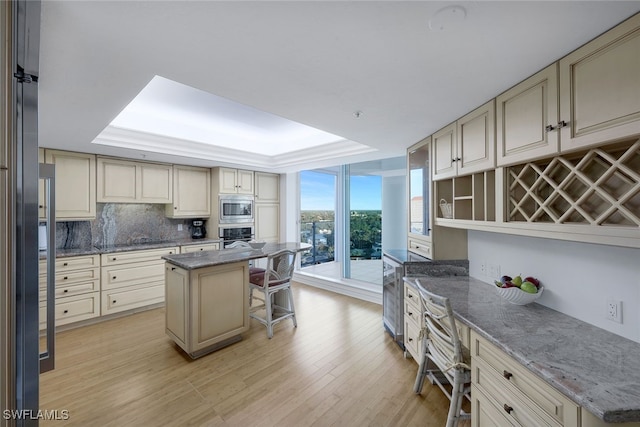 kitchen featuring a breakfast bar area, stainless steel appliances, a center island, cream cabinets, and a raised ceiling