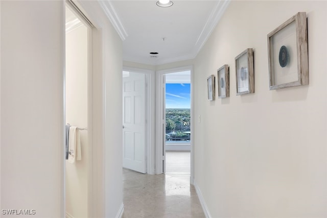 hallway with concrete floors, baseboards, and ornamental molding