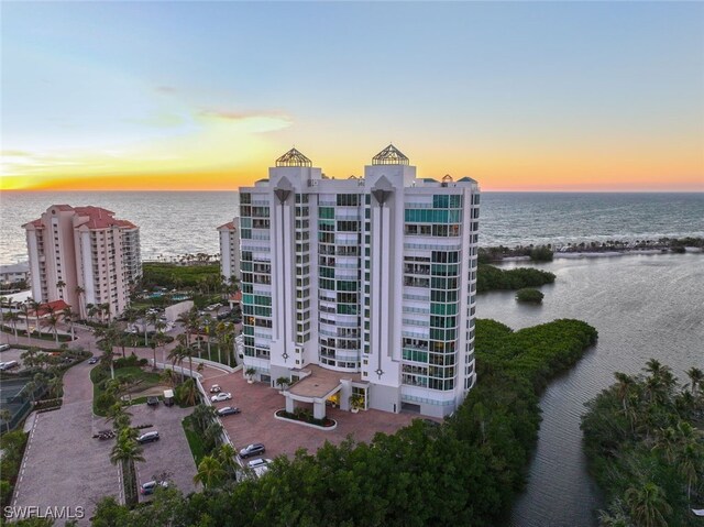 aerial view at dusk featuring a water view