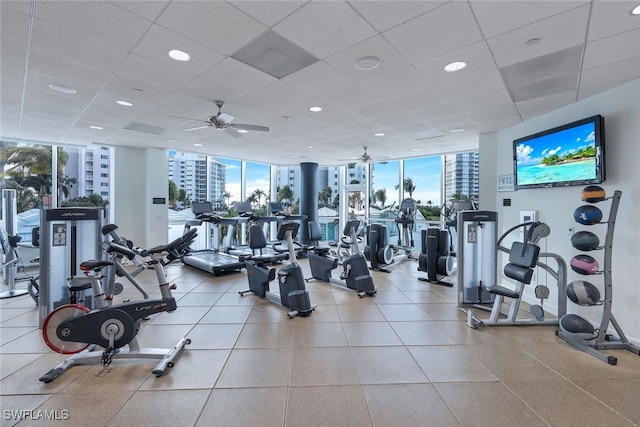 exercise room with expansive windows, ceiling fan, and a paneled ceiling