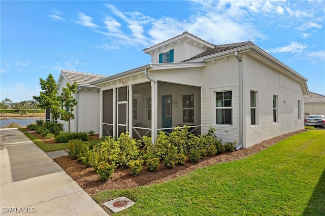 view of side of property featuring a sunroom and a yard