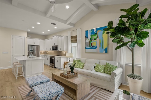 living room with vaulted ceiling with beams and light hardwood / wood-style floors