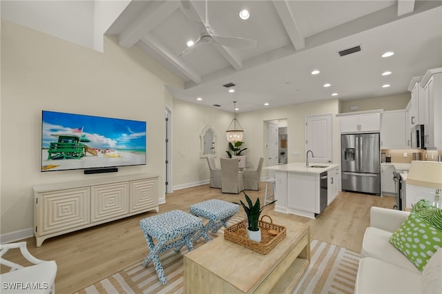 living room with beam ceiling, ceiling fan, sink, and light wood-type flooring