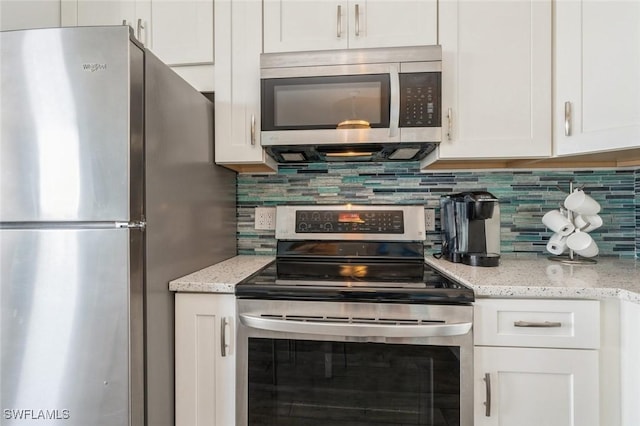 5600 Bonita Beach Rd Unit 508, Bonita Springs, FL 34134 - kitchen with white cabinetry, appliances with stainless steel finishes, light stone counters, and tasteful backsplash