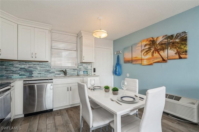 kitchen featuring appliances with stainless steel finishes, white cabinetry, decorative light fixtures, and sink